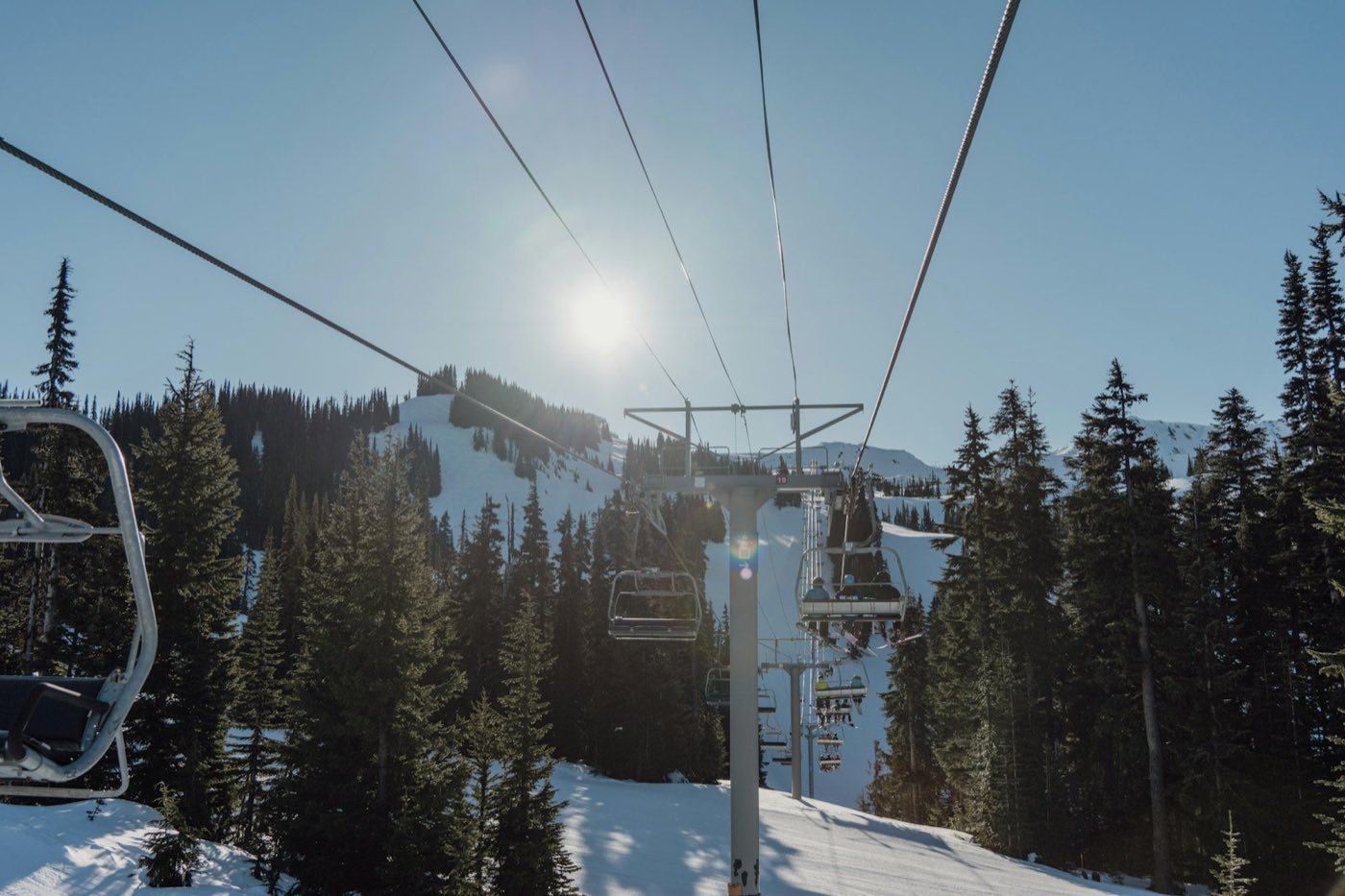 Riding a chairlift above evergreens toward a snowy summit