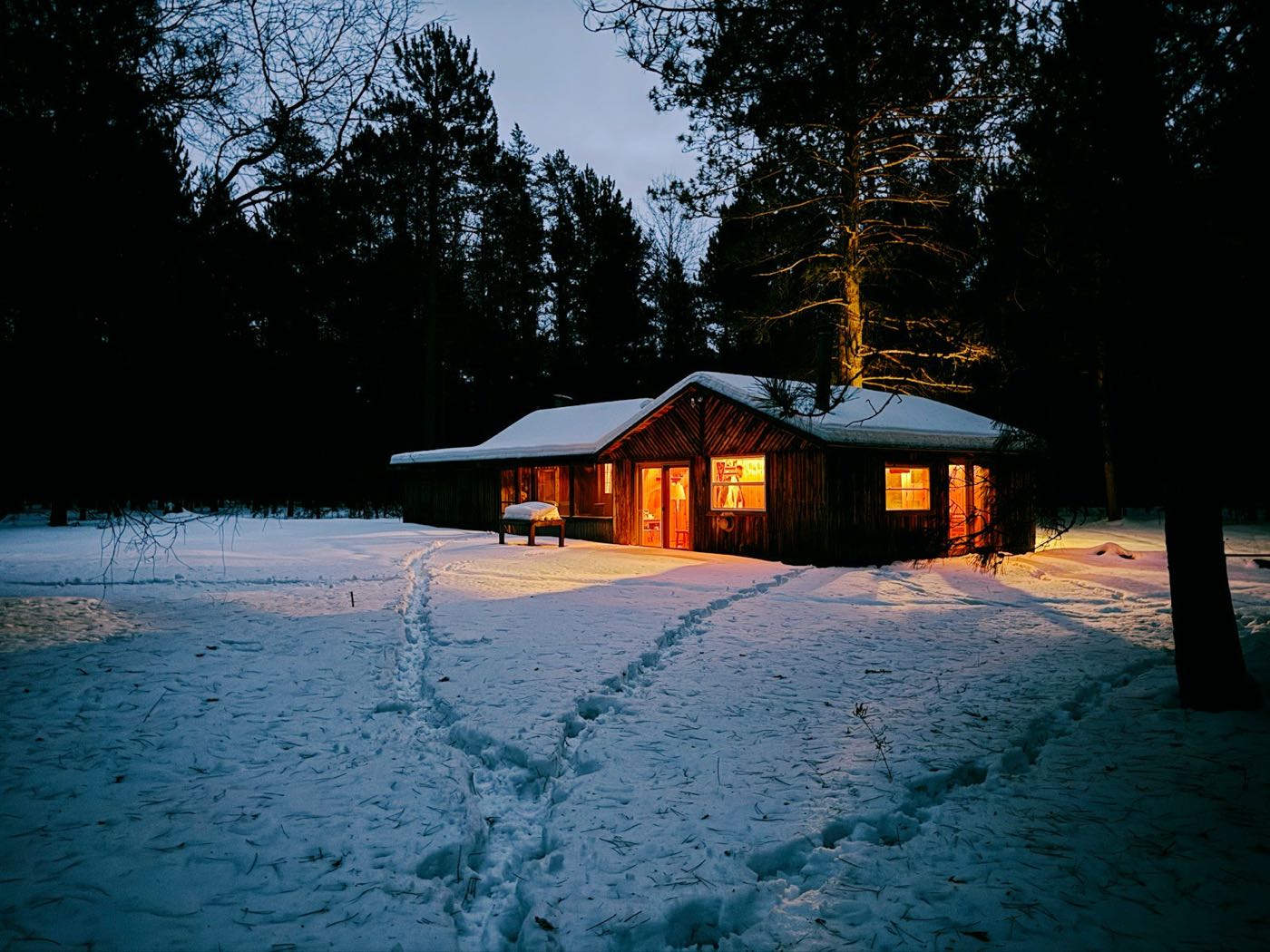 A warm-lit wooden lodge in the snow at dusk